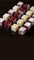 Assorted gourmet Turkish delight lokum cubes with nuts and fruit flavors dusted with powdered sugar on dark wooden surface for confectionery dessert menu.
