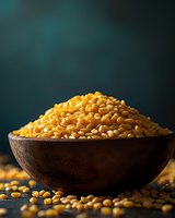 Yellow split peas in rustic wooden bowl against dark green background, dramatic lighting highlights golden legumes, some scattered on dark surface.