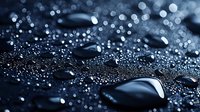 Water drops on dark hydrophobic surface with bokeh effect and selective focus creating abstract macro photography pattern for modern backgrounds.