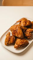 Crispy golden fried chicken wings coated in seasoned breadcrumb crust, served on white plate. Appetizer for restaurants, food blogs, menus.