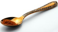 Ornate vintage silver spoon with ground cinnamon powder on white background, isolated culinary still life with antique utensil and aromatic spice.