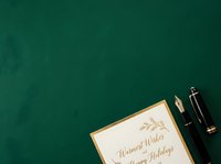 Warm wishes and happy holidays greeting card with elegant gold-trimmed design, fountain pen, and ink bottle on deep teal background for seasonal stationery and festive correspondence.