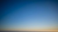 Clear blue sky gradient transitioning to warm golden horizon at sunset or sunrise for backgrounds and design projects.