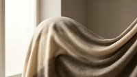 Soft beige fabric draped elegantly with natural lighting creating gentle shadows and texture for interior design and textile concepts.