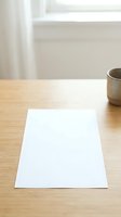 Blank white paper sheet on wooden desk with coffee cup and window light, ready for writing, design, or branding mockup purposes.