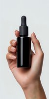 Female hand with manicured nails holding black glass dropper bottle against light gray background, mockup for cosmetic, skincare and wellness products.