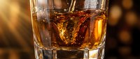 Amber whiskey in crystal glass with golden bokeh lights creating warm atmosphere for luxury bar and restaurant marketing materials.