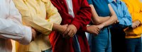 Diverse group of graduates in colorful caps and gowns holding hands in unity during commencement ceremony celebrating academic achievement and friendship.