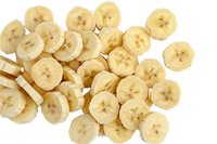 Fresh sliced banana pieces scattered on white background, showing cross-sections with natural star pattern in center, isolated food ingredient for design use.