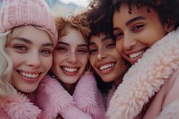 Diverse group of young women in pink winter coats and knitwear sharing joyful moment together. Close-up portrait showcasing genuine friendship, happiness and authentic emotions.