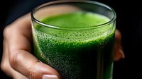 Fresh green vegetable and fruit smoothie in glass held by female hands. Healthy detox drink with wheatgrass, spinach and green ingredients.