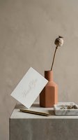 Elegant thank you card leaning against terracotta vase with dried poppy stem, gold pen, and marble tray on neutral stone surface.