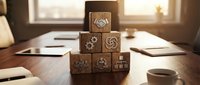 Wooden blocks stacked in pyramid with business icons on desk near coffee cup and papers, representing strategy, planning, and corporate growth for business concepts.