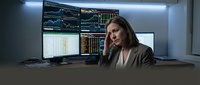 Professional businesswoman trader analyzing financial data on multiple computer monitors in modern trading office environment.