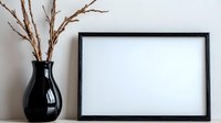 Minimalist mockup with empty black frame and dry branches in black ceramic vase against white wall. Clean modern home decor composition for artwork display.