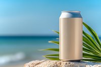 Blank aluminum can mockup on tropical beach with palm leaves and ocean background for beverage branding and packaging design projects.