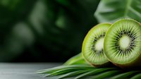 Fresh kiwi fruit slices with tropical palm leaves on wooden surface against green bokeh background for healthy eating and summer concepts.