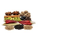 Aromatic spices and herbs collection featuring star anise, cardamom, chili peppers, bay leaves, peppercorns and seeds isolated on white background.