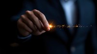 Businessman hand touching glowing light trail with magical sparkle effect in dark background, representing innovation and digital transformation concept.