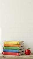 Stack of colorful hardcover books in yellow, orange, green, blue and red with red apple on wooden surface against neutral background for education and learning concepts.