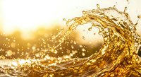 Golden liquid wave splash with droplets and bubbles against warm sunlight background creating dynamic motion and energy for beverage advertising.