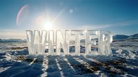 Winter word sculpted from clear ice standing on snowy tundra landscape with bright sun and mountains in background.