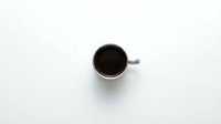 White ceramic coffee cup with black coffee viewed from above on clean white background for minimalist design projects.