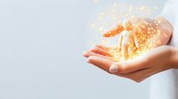Female hands cupped together with magical glowing golden sparkles and light particles floating above palms against light background, concept of hope and magic.