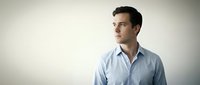 Young professional Caucasian businessman in light blue shirt looking away thoughtfully against neutral background for corporate presentations.