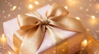 Elegant white gift box with luxurious golden satin ribbon bow against warm bokeh lights background for holiday celebrations and special occasions.