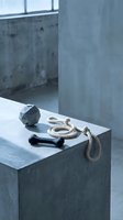 Stylish pet toys on a concrete surface, featuring a geometric ball, black bone, and rope toy in a modern minimalist interior setting.