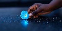 African American woman's hand holding glowing blue flower against dark background with magical sparkles and bokeh effects creating ethereal atmosphere.