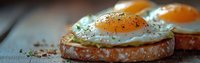 Sunny side up eggs on toasted bread with seasoning, close-up view of breakfast sandwich on rustic wooden table.