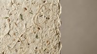 Handmade paper texture with natural fibers and organic materials embedded in cream colored surface for craft projects and artistic backgrounds.
