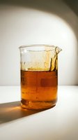 Glass measuring cup filled with amber liquid and ice cubes, backlit by natural sunlight casting shadows on white surface for beverage, cooking, or laboratory use.