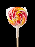 Colorful swirled lollipop with red, orange, and yellow stripes on wooden stick, isolated on transparent background. Ready for clipart, t-shirt designs, stickers, and print-on-demand products.
