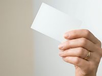 Hand holding blank white card against neutral beige background, suitable for business card mockups, stationery design presentations, and corporate branding applications.