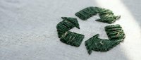 Green recycling symbol embroidered on white fabric texture. Eco-friendly sustainability concept for environmental awareness campaigns and green business materials.