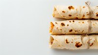 Fresh homemade tortilla wraps rolled and tied with twine on white background, traditional Mexican flatbread with charred spots, ready for serving.