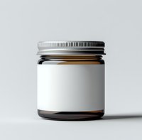 Empty amber glass jar with metal lid and blank white label on light background, isolated product mockup for cosmetics, food or medicine packaging.