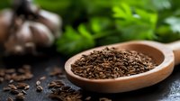 Organic cumin seeds in wooden spoon on dark background with fresh herbs and garlic cloves, macro food photography for cooking and seasoning concept.