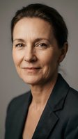 Middle-aged woman with dark hair wearing charcoal blazer against neutral background. Suitable for corporate, business, professional profiles, leadership, executive portraits.