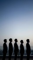 Five businessmen silhouettes standing in line against twilight sky overlooking city skyline for corporate teamwork and leadership concepts.