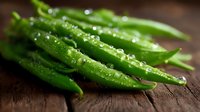 Fresh green string beans with water droplets on rustic wooden surface in macro view, natural organic produce for healthy cooking and food blogs.