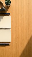 Flat lay of spiral notebook, pens, coffee cup, and succulent on a warm wooden desk with copy space for business or lifestyle use.
