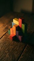 Colorful wooden blocks arranged in geometric puzzle formation on rustic wood surface creating abstract architectural structure for creative play and learning.