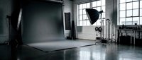 Professional photography studio with gray backdrop, lighting equipment and softboxes for commercial photo shoots and video production.