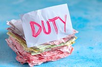 Stack of crumpled colorful paper notes with duty word written in pink marker on top against blue background, representing overwhelming tasks and responsibilities.