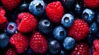 Fresh ripe raspberries and blueberries macro background with water drops, healthy organic berries closeup pattern for natural food design.