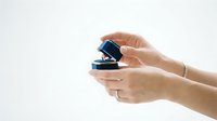 Female hands holding stacked blue and black jewelry boxes against white background, isolated for design use on packaging, marketing materials, and retail presentations.